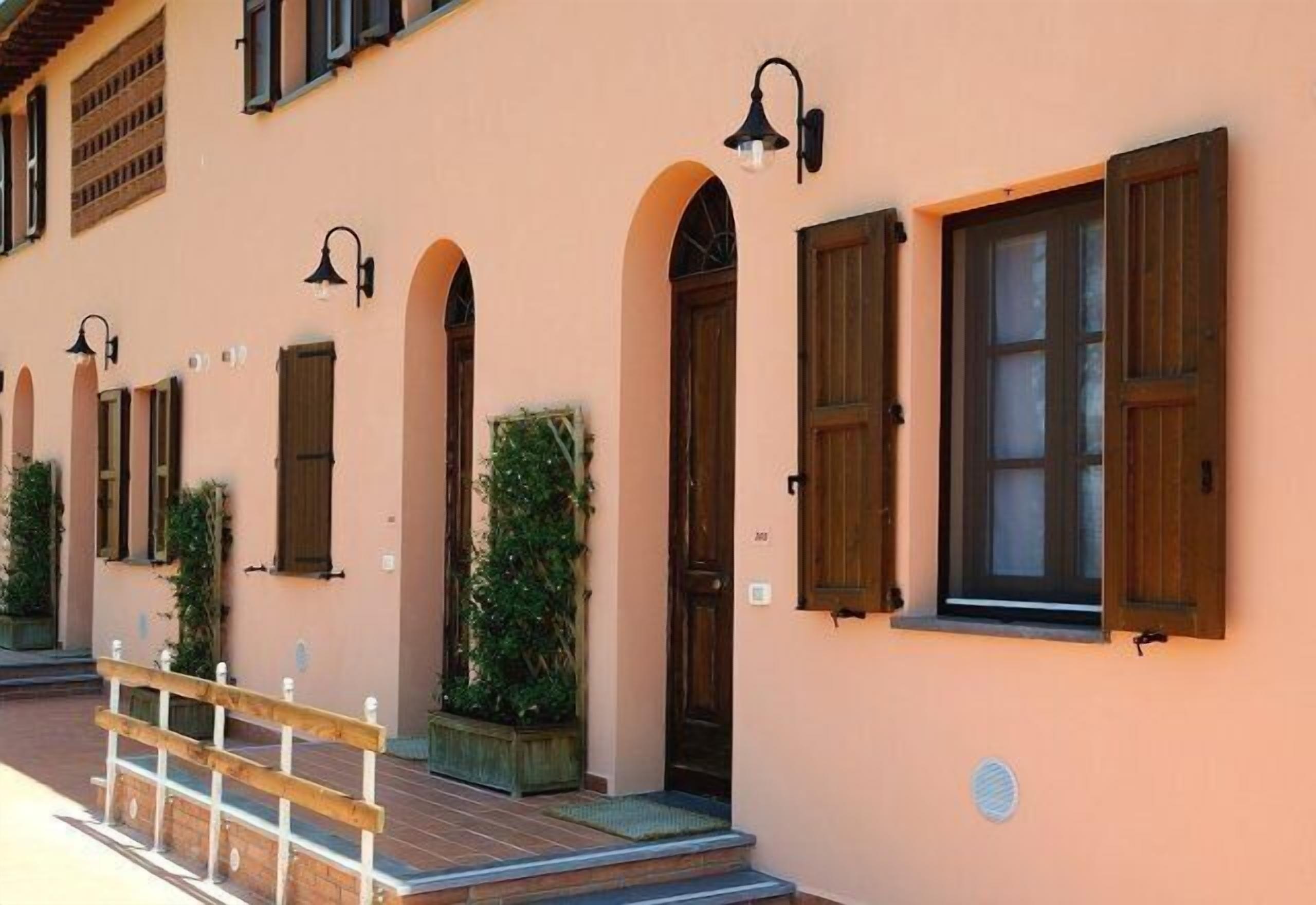 A building with multiple windows, some with shutters, and a wooden railing in front.