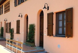 A building with multiple windows, some with shutters, and a wooden railing in front. - Corte Tommasi Residence (Castelfranco di Sotto)