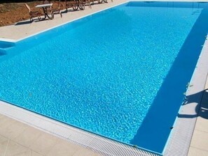 A rectangular swimming pool with clear blue water, surrounded by a tiled deck and a few lounge chairs. - Corte Tommasi Residence (Castelfranco di Sotto)