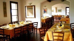 A dining area with multiple tables set for meals, wooden chairs, and a tiled floor. - Corte Tommasi Residence (Castelfranco di Sotto)