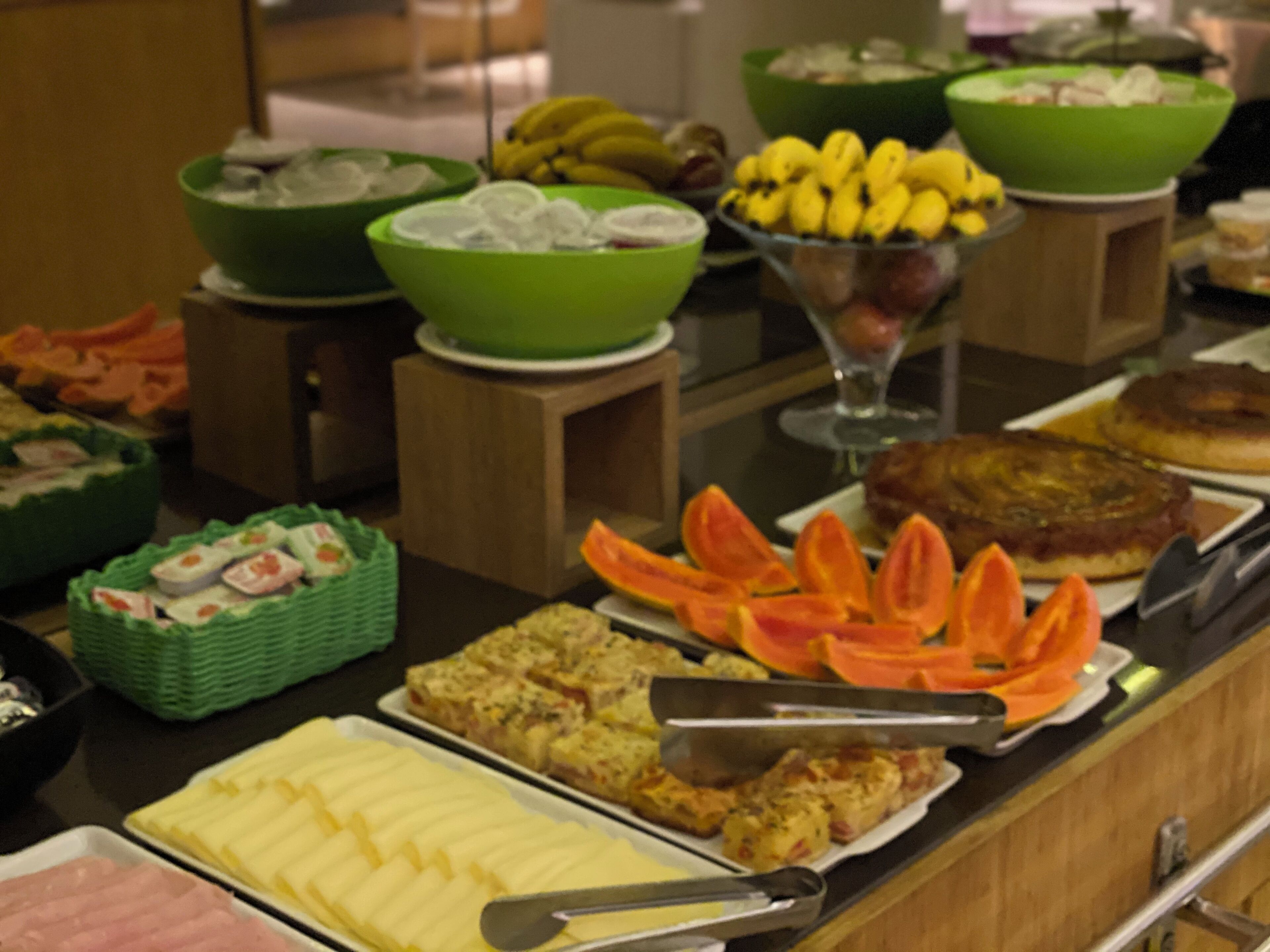 A buffet with various food items including sliced fruits, vegetables, and prepared dishes.