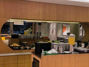 A breakfast bar with a variety of food items, including fruits, pastries, and beverages. - DMax Hotel (Marilia)