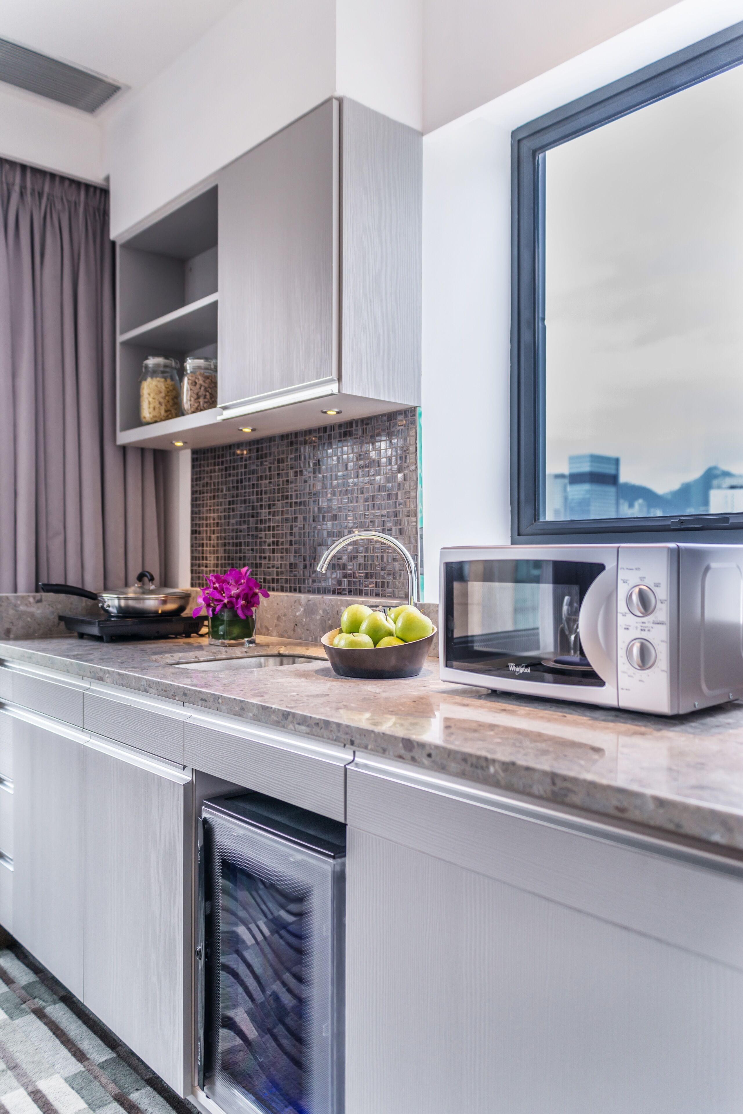 A modern kitchen with a built-in microwave, a sink, and a window above the counter.