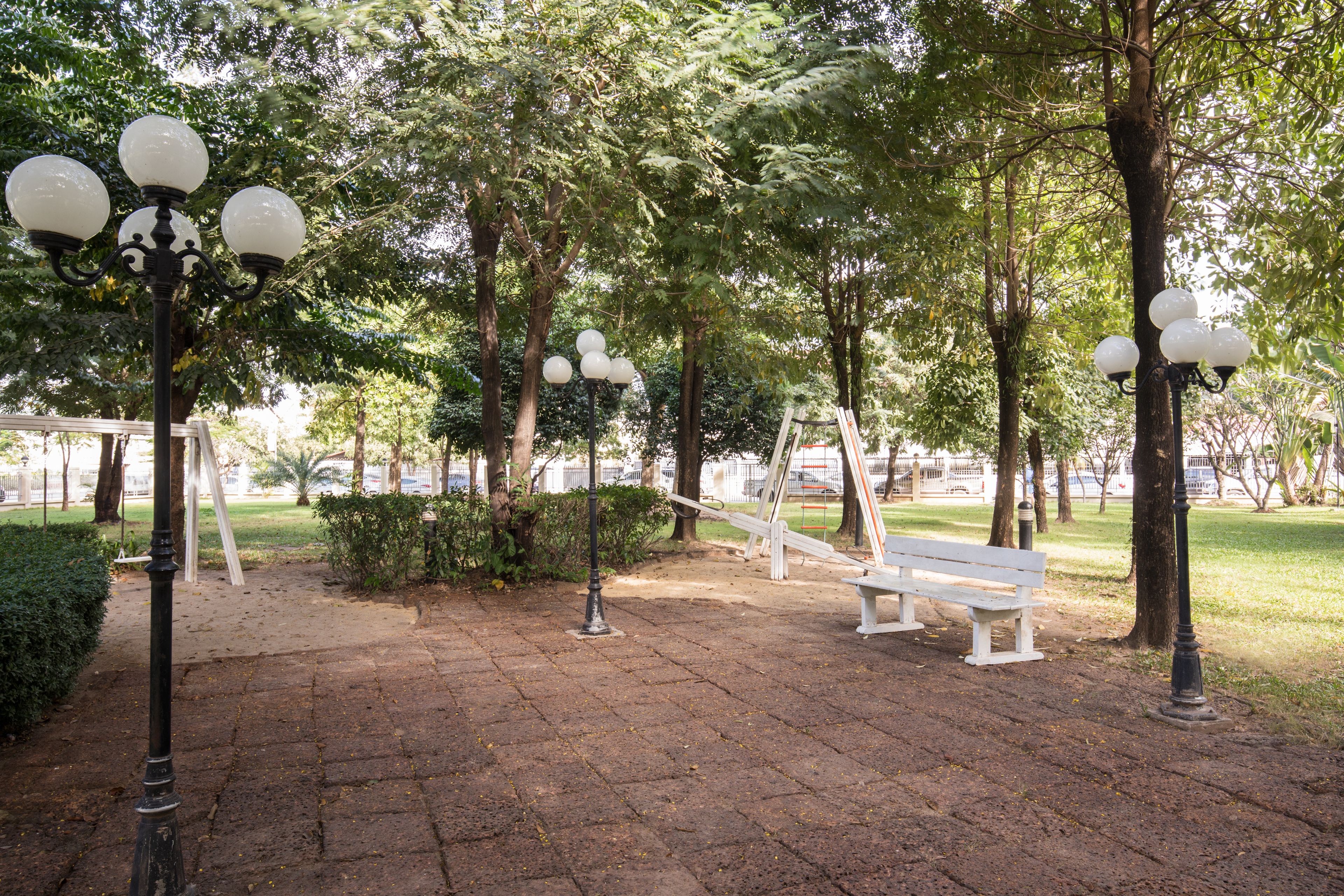 Ein Park mit einem gepflasterten Weg, Bänken und Straßenlaternen.