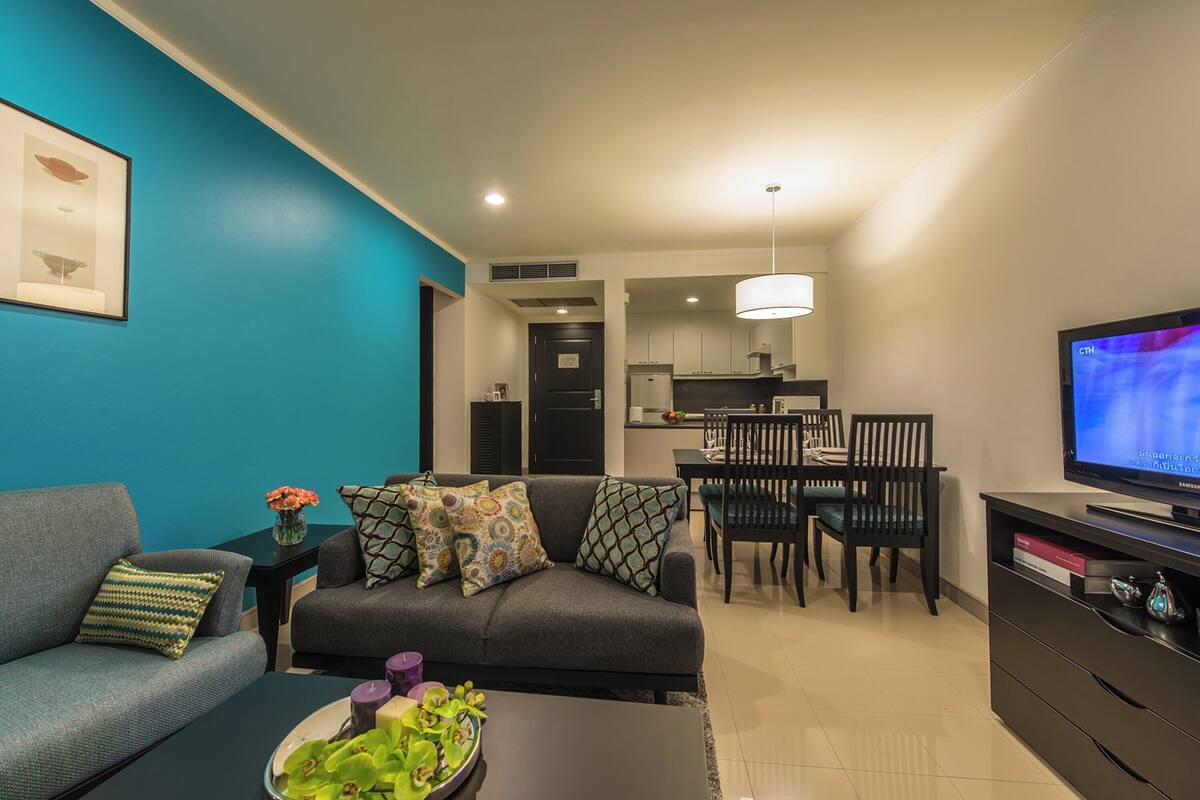 A modern living room with a sofa, coffee table, and a dining area with chairs and a table.