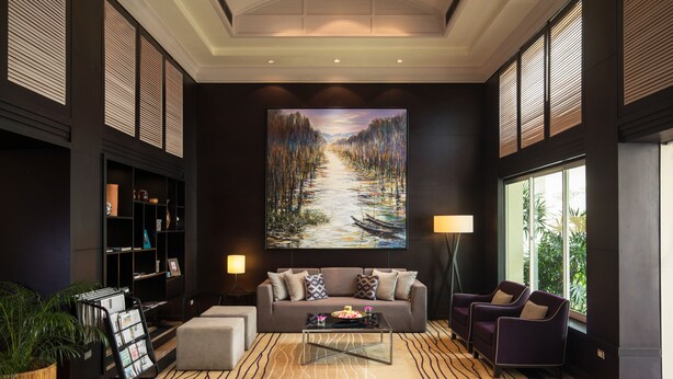 A modern lobby with a large painting, a sofa, armchairs, a coffee table, and a bookshelf. - Somerset Vientiane (Vientiane)