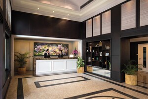 A reception area with a reception desk, a large floral painting, and a bookshelf with decorative items.