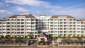 A large, multi-story hotel with a symmetrical facade, multiple balconies, and a central entrance with flags. - Somerset Vientiane (Vientiane)
