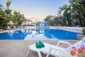 Una piscina al aire libre, sillones reclinables de piscina