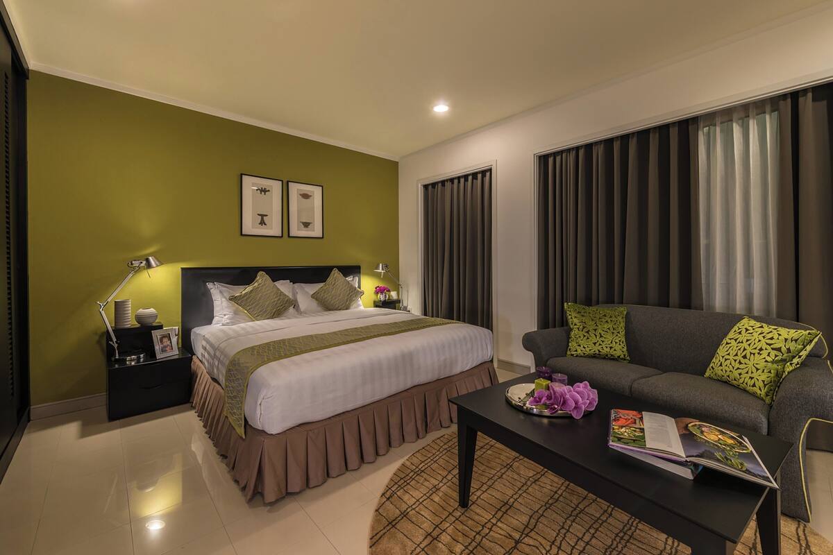 A hotel room with a bed, a sofa, a coffee table, and a nightstand.