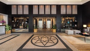 A spacious lobby with a geometric floor design, a reception desk, and a seating area with a lamp and cushions. - Somerset Vientiane (Vientiane)