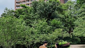 A couple walking on a patterned pathway in a park with a building in the background.