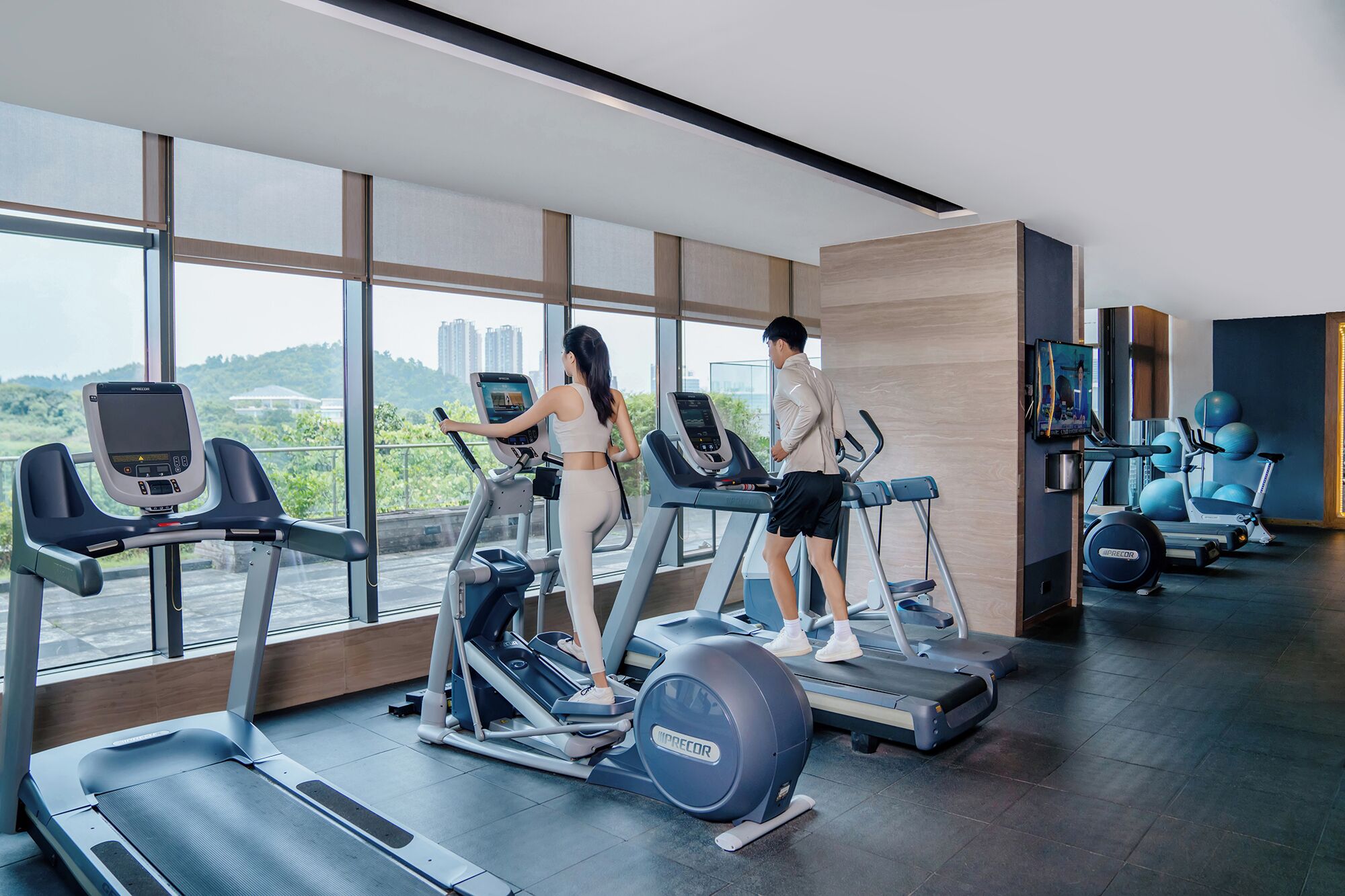 A modern gym with treadmills, elliptical machines, and exercise balls.