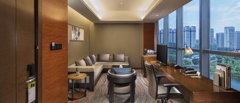 Habitación de hotel moderna con sofá, escritorio y vista a la ciudad.
