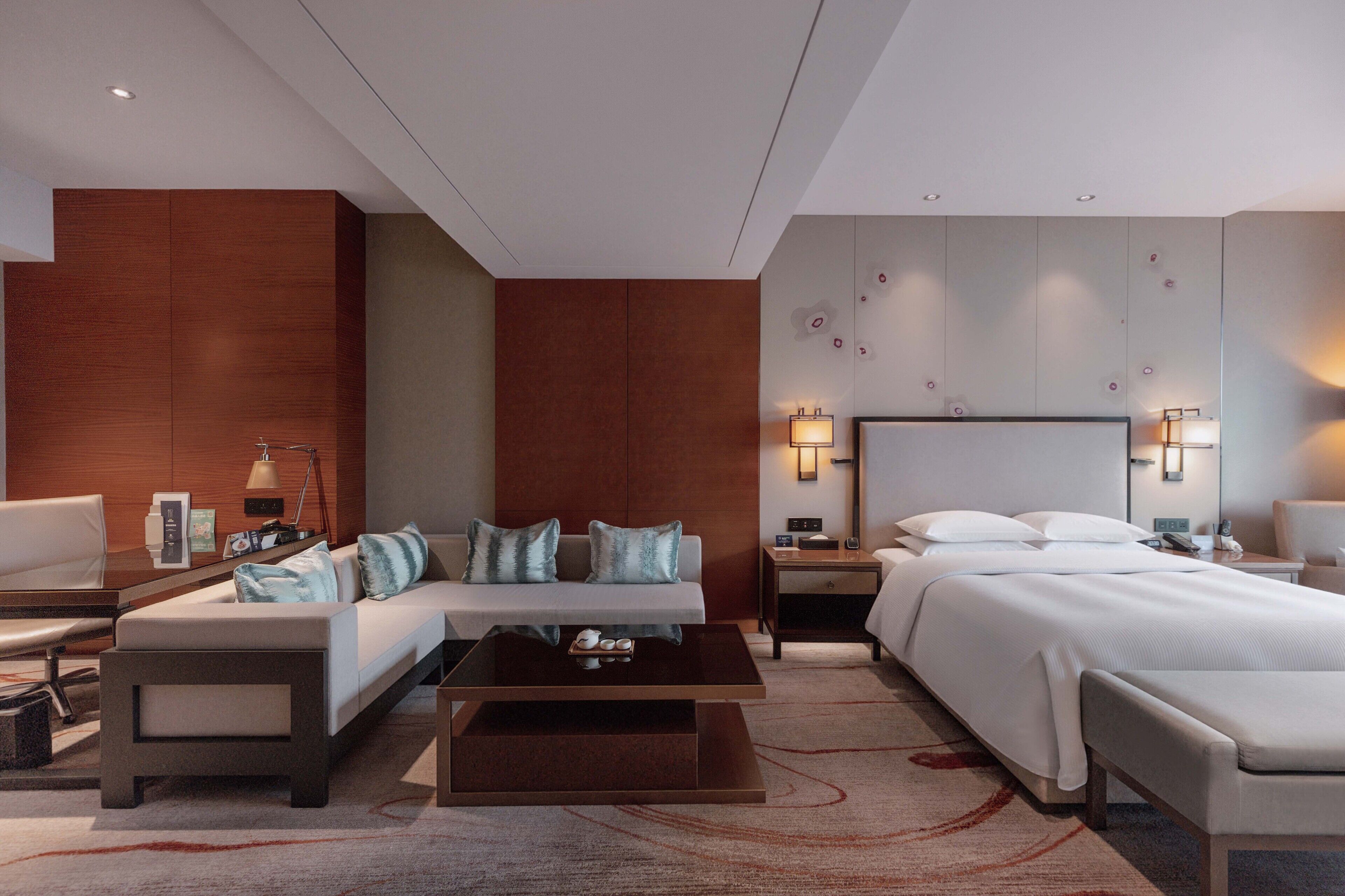 A modern hotel room with a bed, sofa, and coffee table.