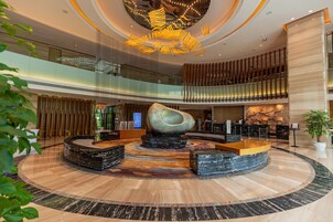 Un'ampia hall con un'area salotto centrale, una reception e un moderno lampadario.