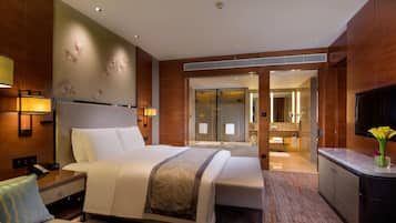 Ein Hotelzimmer mit Bett, Nachttisch, Lampe und Blick ins Bad.