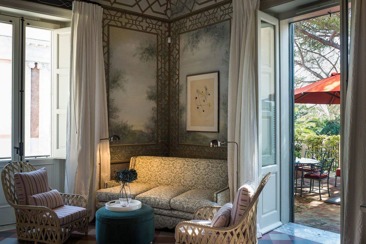 A cozy room with a patterned sofa, wicker chairs, and a small table with a vase.