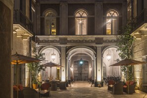 Un patio con mobiliario exterior, columnas y una puerta central.