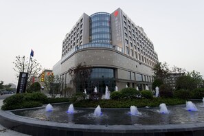 A modern hotel with a curved facade, multiple floors, and a central courtyard with fountains. - Yang Peng Jin Jiang Hotel (Yangzhou)
