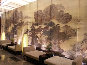 Un vestíbulo con arte mural de estilo chino tradicional, zonas de estar y un diseño de suelo moderno.