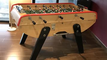 A foosball table in a room with wooden flooring and a window.