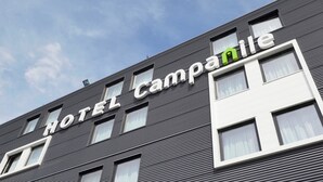 Un edificio de hotel con fachada moderna, que muestra un letrero que dice "HOTEL Campanile".