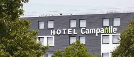 Un hotel llamado "HOTEL Campanile" con un diseño arquitectónico moderno, que cuenta con múltiples ventanas y un techo plano.