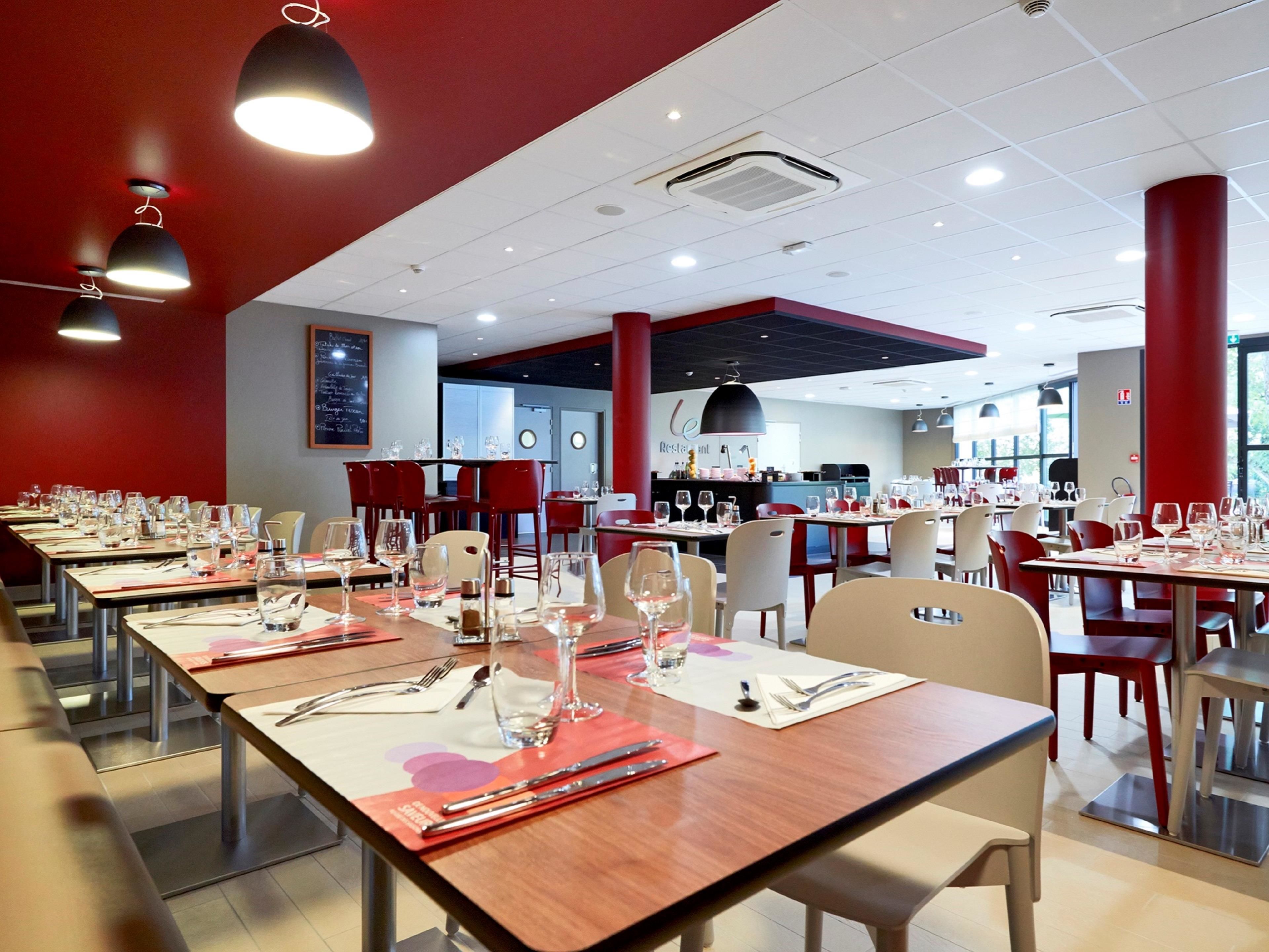 Un restaurante con varias mesas dispuestas para comer, provistas de cubiertos y copas.