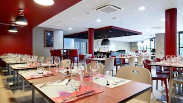 A restaurant with multiple tables set for dining, equipped with cutlery and glasses.