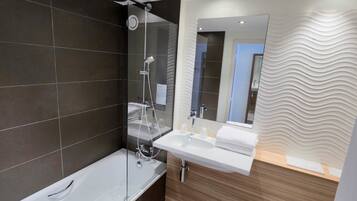 A modern bathroom with a glass-enclosed shower, a standalone bathtub, and a vanity with a mirror.