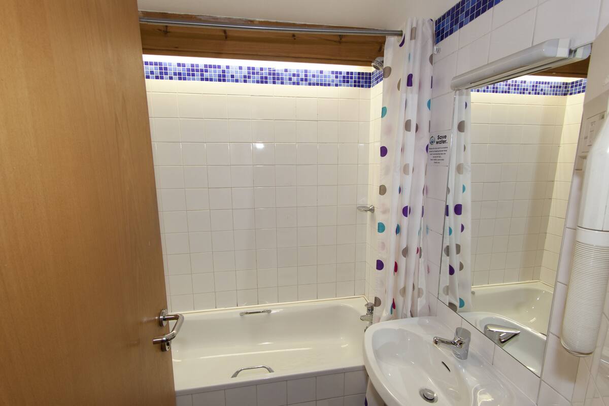 A bathroom with a bathtub, a sink, and a shower curtain.