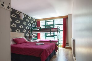 A dormitory room with bunk beds, a desk, and a window with red curtains. - Abigails Hostel (Dublin)