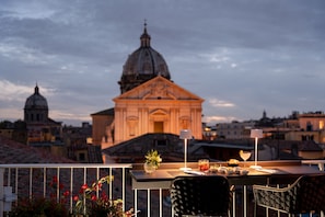Una terraza con una mesa lista para comer, con vista a un edificio histórico con una cúpula y un campanario.