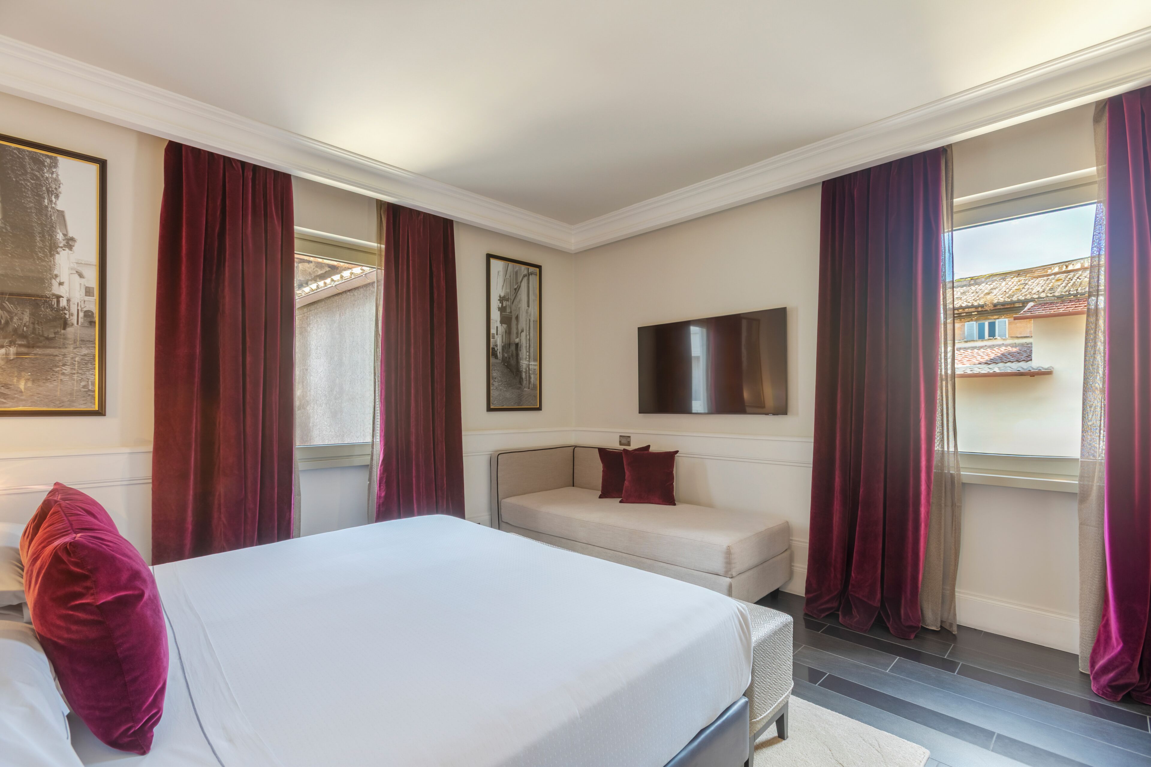 Un dormitorio con cama, sofá, televisor y cortinas.