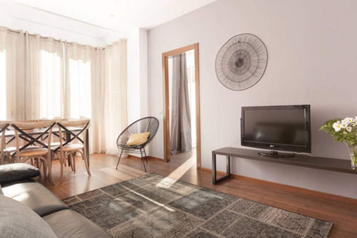 Uma sala de estar moderna com sofá, TV e área de jantar.