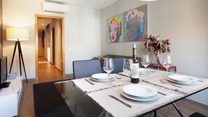 A modern dining area with a glass table set for two, a television, and a lamp. - Easy Sleep Eixample  (Barcelona)