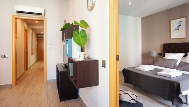 A hotel room with a bed, bedside table, wall clock, and a framed bird painting. - Easy Sleep Eixample  (Barcelona)