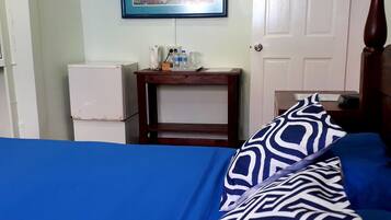 Un dormitorio con cama, mesita de noche, un cuadro enmarcado en la pared y una puerta.