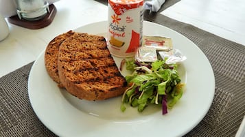 A plate with a slice of pineapple cake, a can of Yoplait Original, and a salad with butter packets.