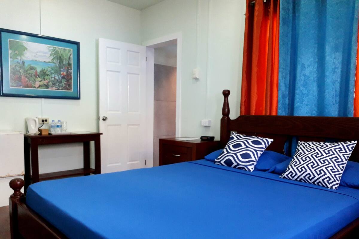 A bedroom with a wooden bed, blue bedding, and patterned pillows.