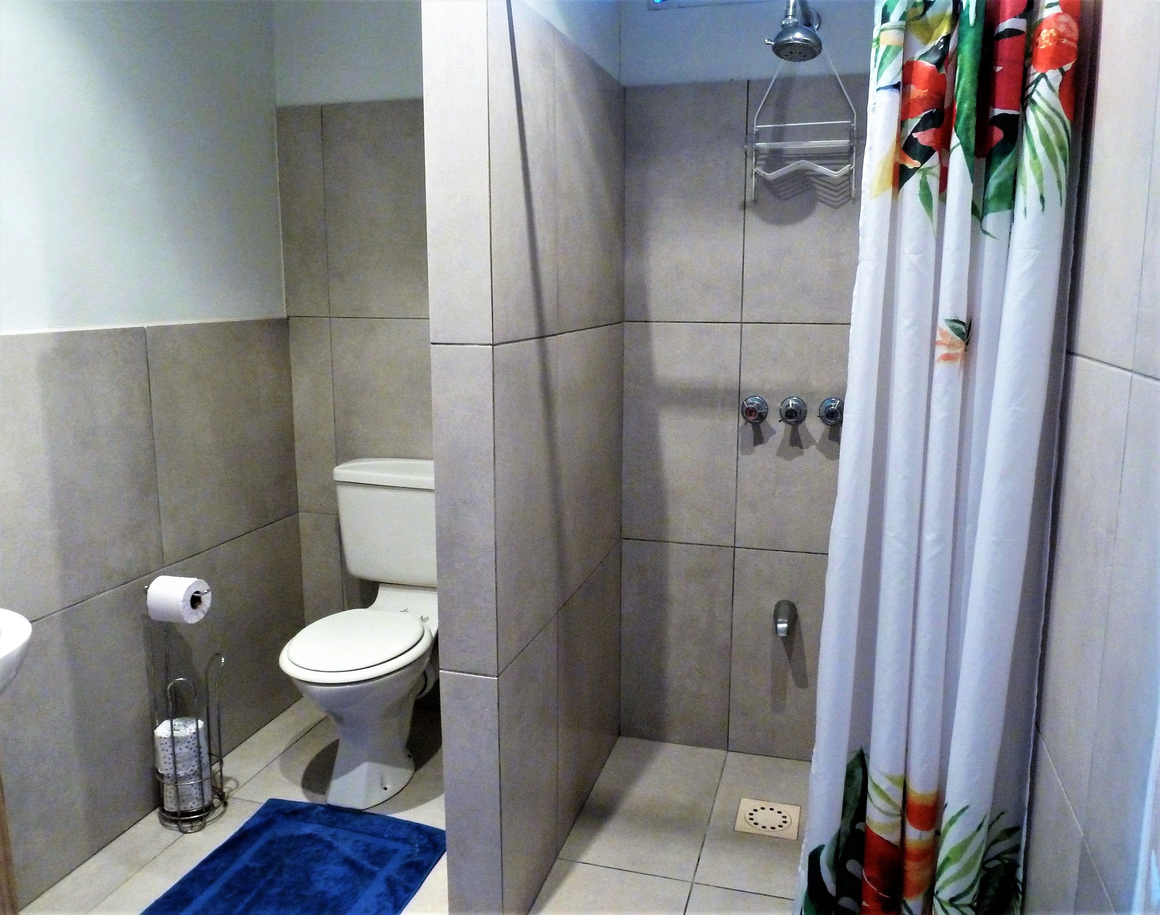 A bathroom with a toilet, shower, and sink.