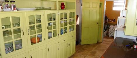 Una cocina con armarios verdes, una encimera y una puerta que da a otra habitación.