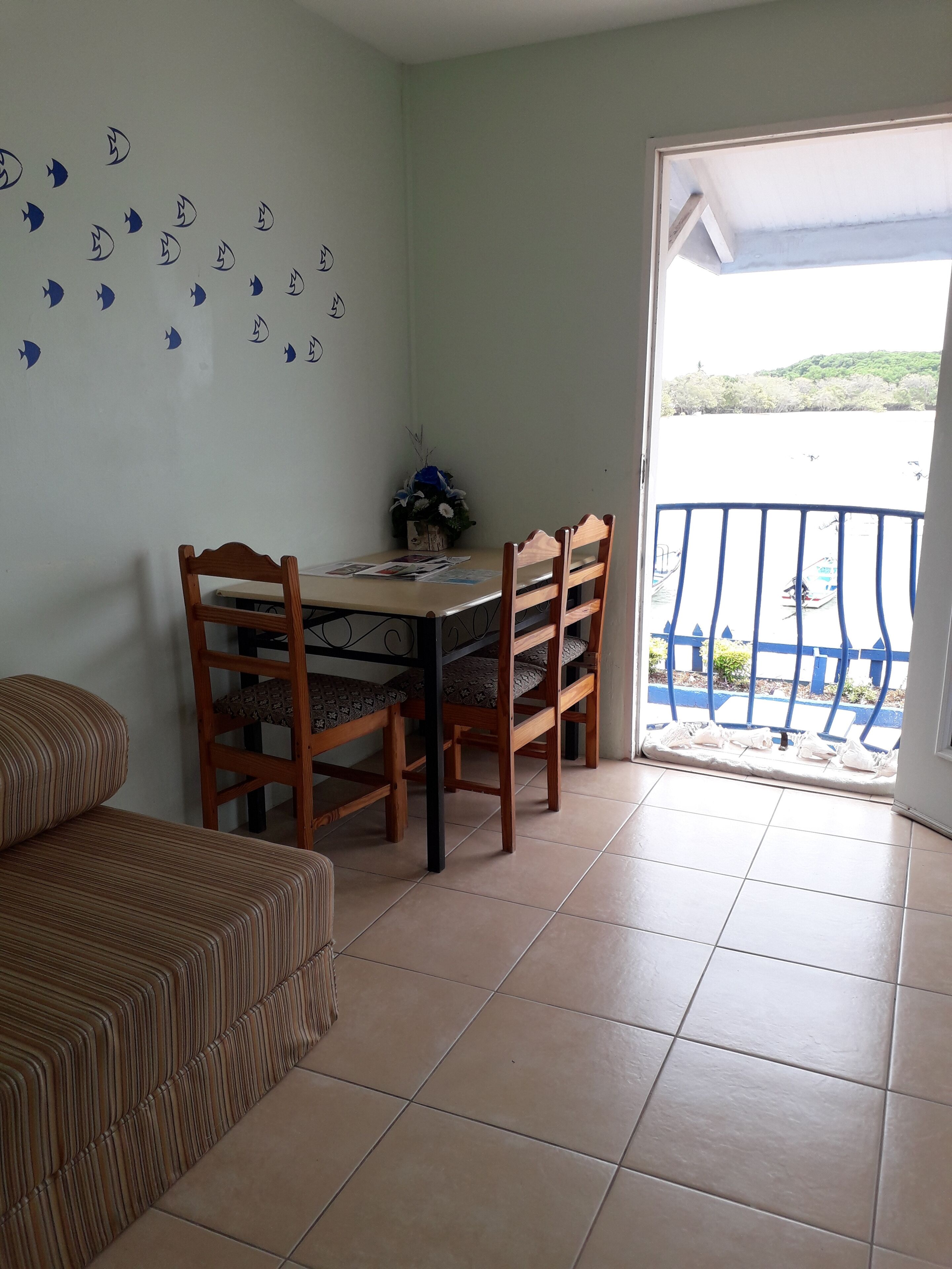 Un coin repas comprenant une table et des chaises, un canapé et une vue sur un balcon doté d’une balustrade.