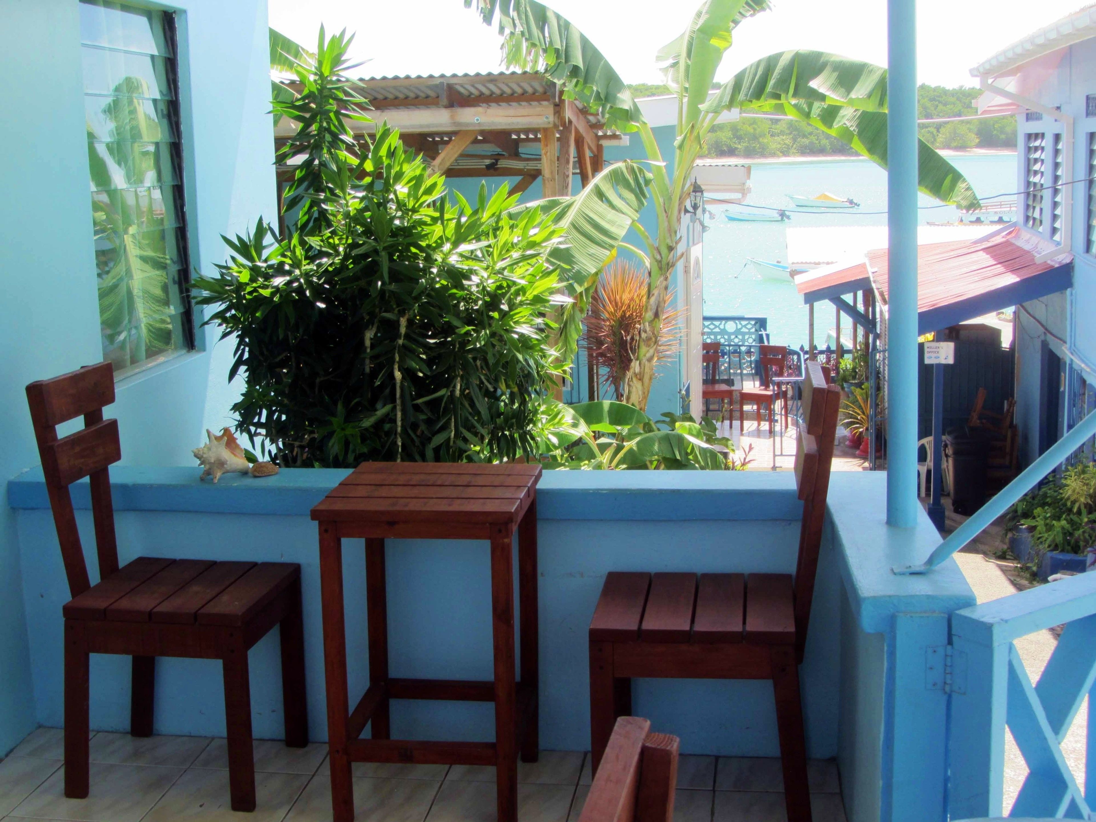 Un balcón con sillas y una mesa de madera, rodeado de exuberante follaje tropical.