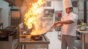 A chef in a professional kitchen with a large flame on a wok. - The Lakeside Hotel at Nuwarawewa (Anuradhapura)