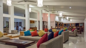 A spacious living area with multiple sofas and armchairs, a coffee table, and ceiling fans. - The Lakeside Hotel at Nuwarawewa (Anuradhapura)