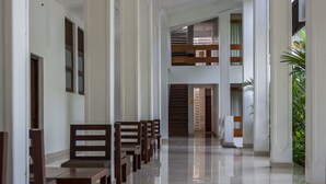 A spacious hallway with wooden benches, a polished floor, and a staircase leading to an upper level. - The Lakeside Hotel at Nuwarawewa (Anuradhapura)