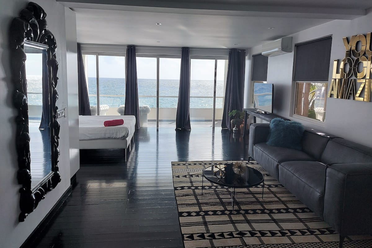 Une chambre d’hôtel moderne dotée d’un grand balcon, d’un lit, d’un canapé et d’une télévision.