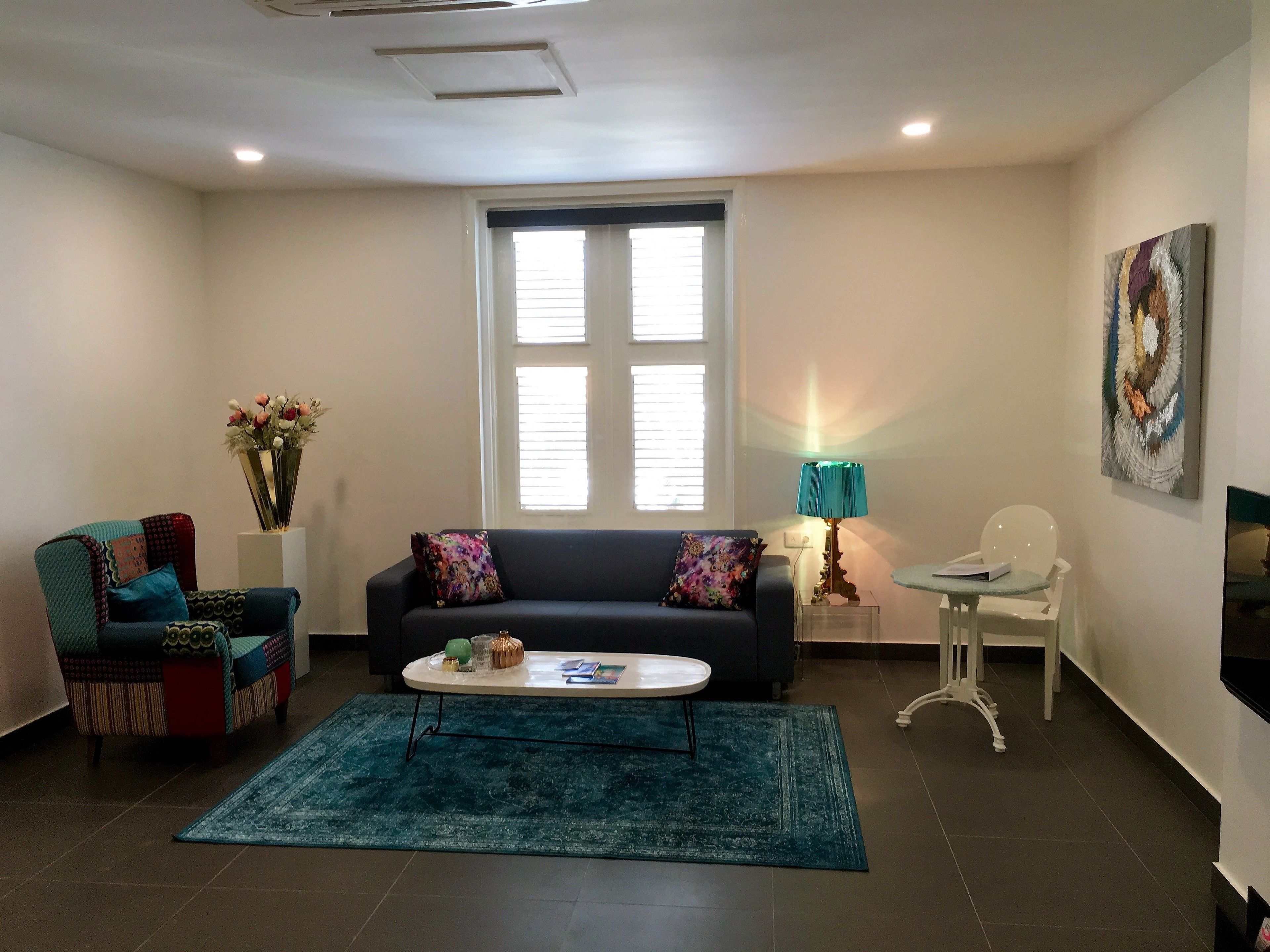 A living room with a sofa, a coffee table, a lamp, a chair, and a painting on the wall.